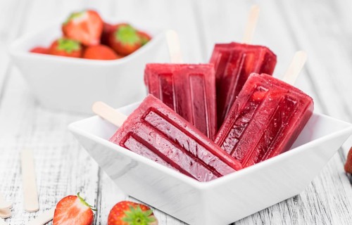 Old wooden table with homemade Strawberry Popsicles (close-up shot, selective focus)