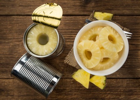 Preserved Pineapple Rings as high detailed close-up shot on a vintage wooden table, selective focus