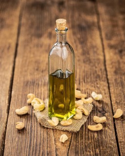 Fresh made Cashew Oil on an old wooden table (close-up shot, selective focus)
