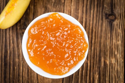 Wooden table with Peach Jam (selective focus, close-up shot)