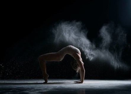 Modern art. Dancer performs acrobatic trick in cloud of dust
