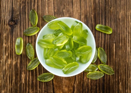 Heap of gummy candy with lime taste on wooden background (selective focus, close-up shot)