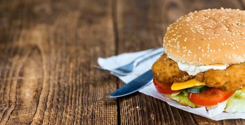 Wooden table with a fresh made Fish Burger (close-up shot, selective focus)