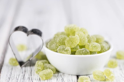 Sour gummy candy (apple taste) on an old wooden table (selective focus)