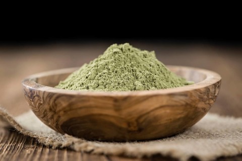 Portion of Stevia leaf powder (detailed close-up shot) on rustic wooden background