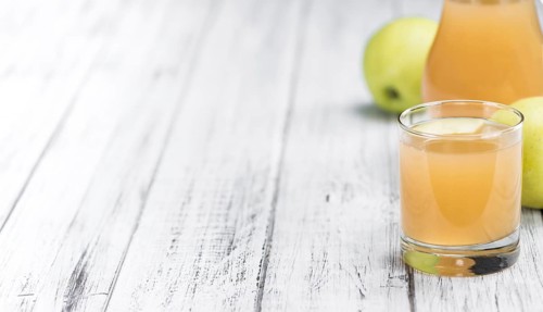 Apple Juice on an old wooden table as detailed close-up shot (selective focus)