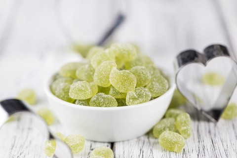 Portion of gummy candy (apple taste) on an old wooden table