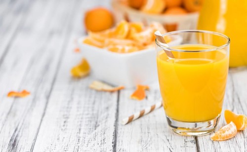 Homemade Tangerine Juice on an old and rustic wooden table (selective focus, close-up shot)