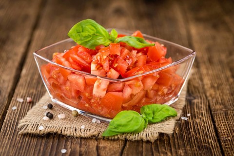 Tomatoes (diced) as high detailed close-up shot on a vintage wooden table (selective focus)