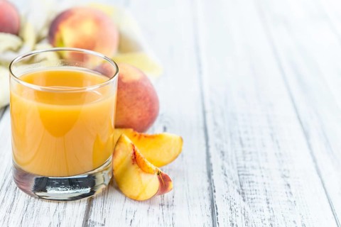 Fresh made Peach juice (detailed close-up shot) on wooden background