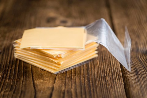 Cheese (sliced) on an old wooden table as detailed close-up shot (selective focus)