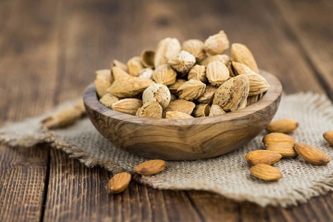 Roasted Almonds (in shell) on an old wooden table (close-up shot, selective focus)