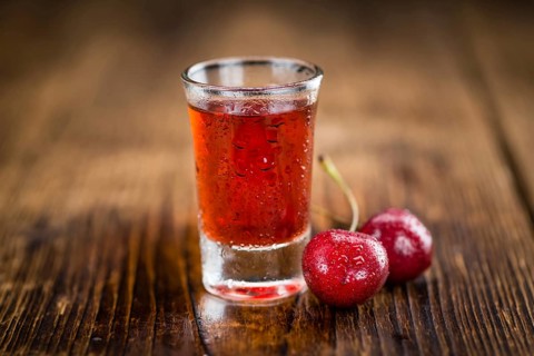 Cherry Liqueur as high detailed close-up shot on a vintage wooden table, selective focus