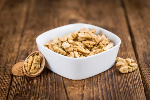 Walnuts (kernels) on an old wooden table as detailed close-up shot (selective focus)