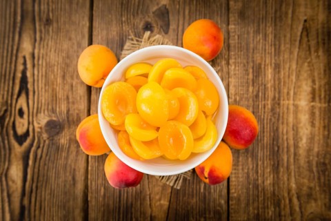 Canned Apricots on rustic wooden background (close-up shot)