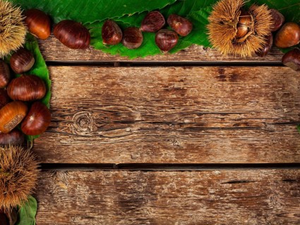 Frame of chestnuts, leaves and chestnut bur on wooden table