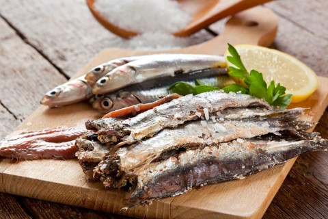 Marinated anchovies with salt and lemon on wooden table
