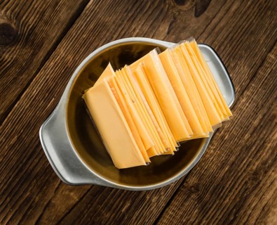 Cheese (sliced) on an old wooden table as detailed close-up shot (selective focus)