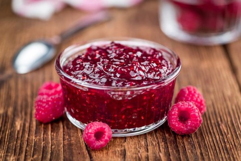 Homemade Raspberry Jam on an wooden table as detailed close-up shot, selective focus