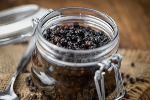 Preserved black Peppercorns on wooden background, selective focus, close-up shot