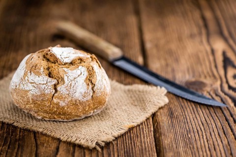 Wholemeal Roll on rustic wooden background (close-up shot)