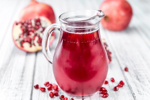 Pomegranate juice as high detailed close-up shot on a vintage wooden table (selective focus)