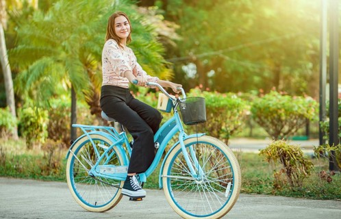Portrait of beautiful smiling young woman riding a bicycle at sunset, looking at camera