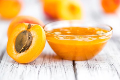 Apricot Jam on an old wooden table as detailed close-up shot (selective focus)