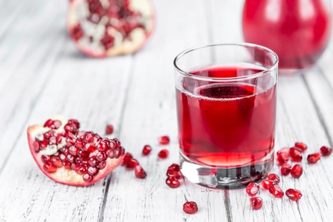 Pomegranate juice as high detailed close-up shot on a vintage wooden table (selective focus)