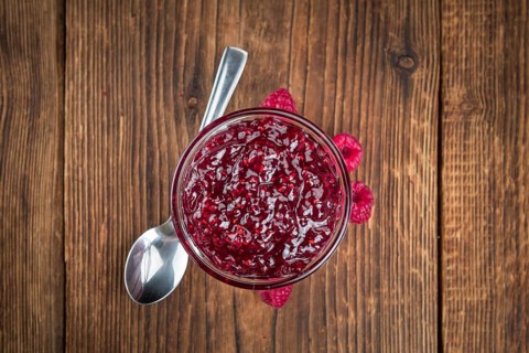 Homemade Raspberry Jam on an wooden table as detailed close-up shot, selective focus