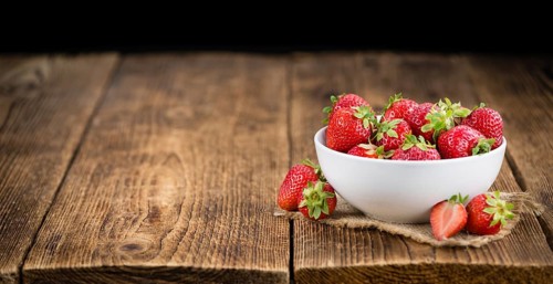 Strawberries on an old wooden table as detailed close-up shot, selective focus