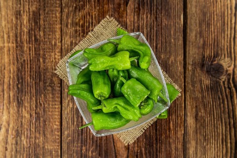 Raw Pimientos on rustic wooden background as close-up shot