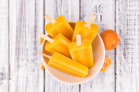 Homemade Tangerine Popsicles with some fresh fruits (close-up shot) on a vintage background