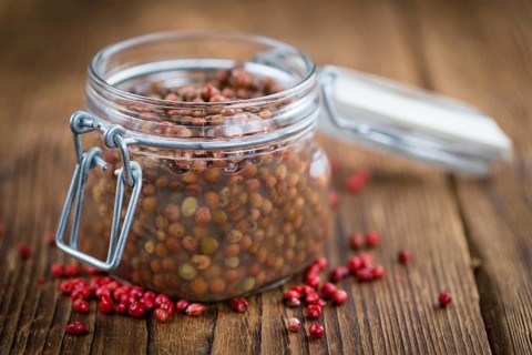 Preserved Pink Peppercorns on a vintage background as detailed close-up shot, selective focus