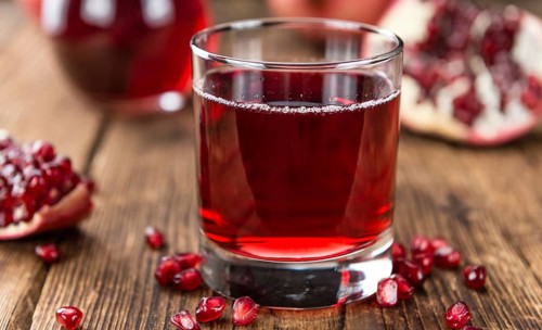 Homemade Pomegranate juice on an wooden table (selective focus) as detailed close-up shot