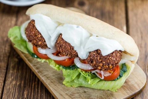 Wooden table with a fresh made Falafel Sandwich (selective focus, close-up shot)