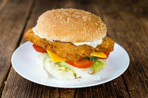 Wooden table with a fresh made Fish Burger (close-up shot, selective focus)