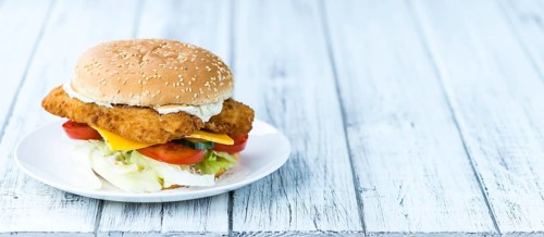 Homemade Fish Burger (close-up shot, selective focus) on a wooden table
