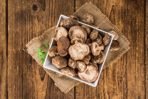 Shiitake mushrooms on an old wooden table as detailed close-up shot, selective focus