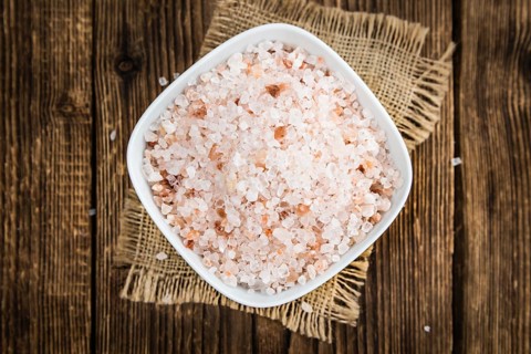 Salt (pink) on an old wooden table as detailed close-up shot (selective focus)