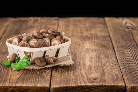 Raw Shiitake mushrooms as high detailed close-up shot on a vintage wooden table, selective focus