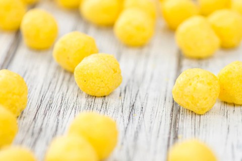 Cheese Balls on an old wooden table as detailed close-up shot (selective focus)