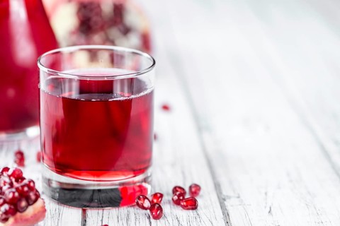 Homemade Pomegranate juice on an wooden table (selective focus) as detailed close-up shot