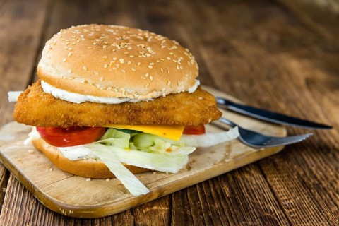 Fish Burger on wooden background (close-up shot, selective focus)