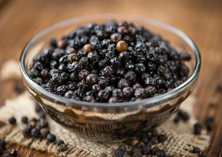 Preserved black Peppercorns on wooden background, selective focus, close-up shot
