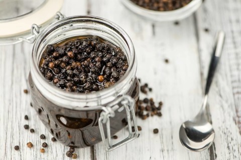 Preserved black Peppercorns on wooden background, selective focus, close-up shot
