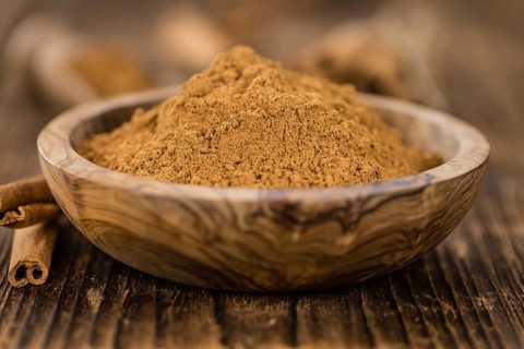 Cinnamon Powder as high detailed close-up shot on a vintage wooden table (selective focus)
