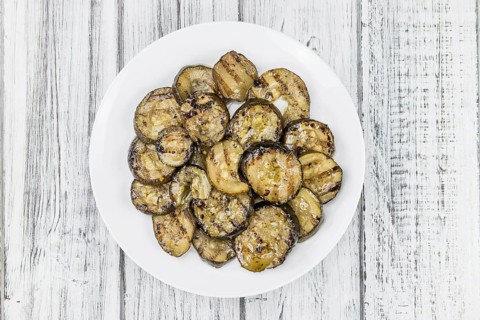 Zucchinis (grilled) as high detailed close-up shot on a vintage wooden table (selective focus)