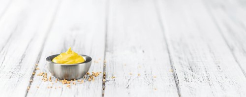 Fresh made Mustard on a vintage background (close-up shot)