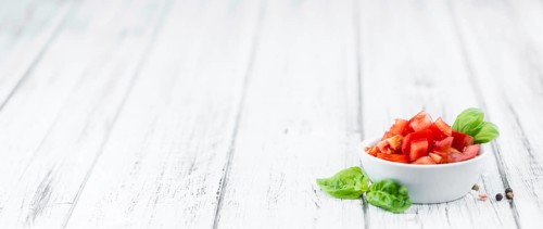 Cutted Tomatoes on an old wooden table as detailed close-up shot (selective focus)